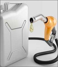 Un bidón de combustible de metal plateado junto a la boquilla de una bomba de combustible de color naranja, de cuya punta cae una sola gota de líquido amarillo.