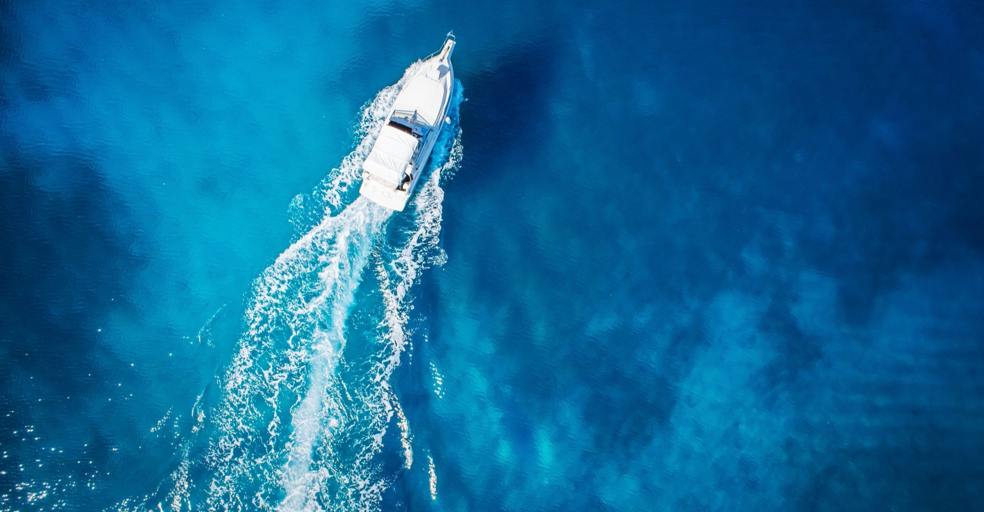 Vue du ciel sur un bateau qui avance sur une eau bleue