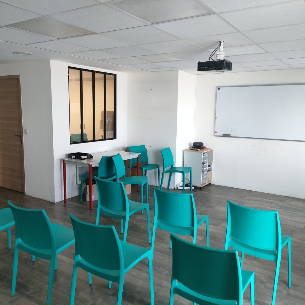 Salle de formation avec des chaises face à un tableau blanc