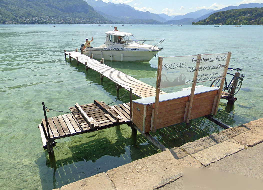 Bateau école avec des personnes à bord, devant le ponton Violland sur le lac
