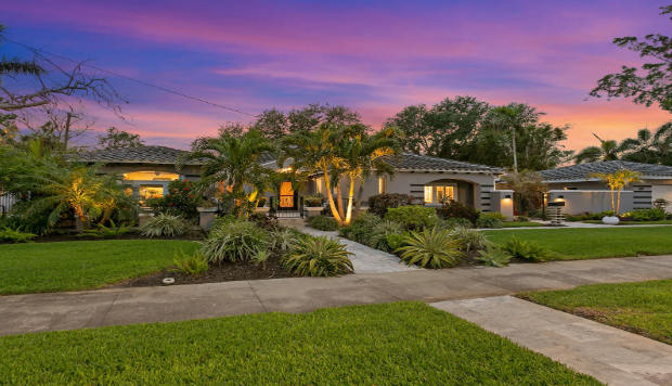 House exterior with landscaped yard at dusk, purple and orange sky.
