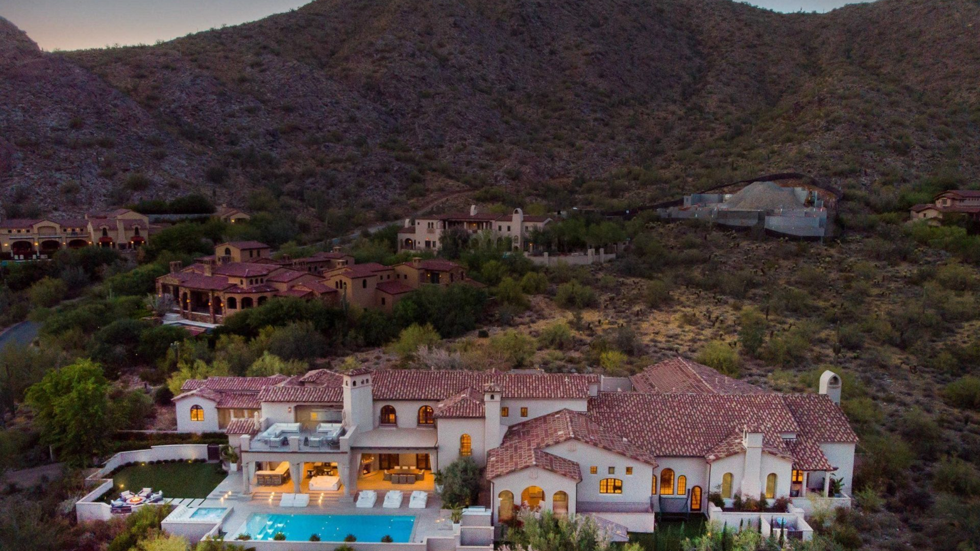Large luxury homes with red-tile roofs nestled in a desert hillside with a swimming pool.