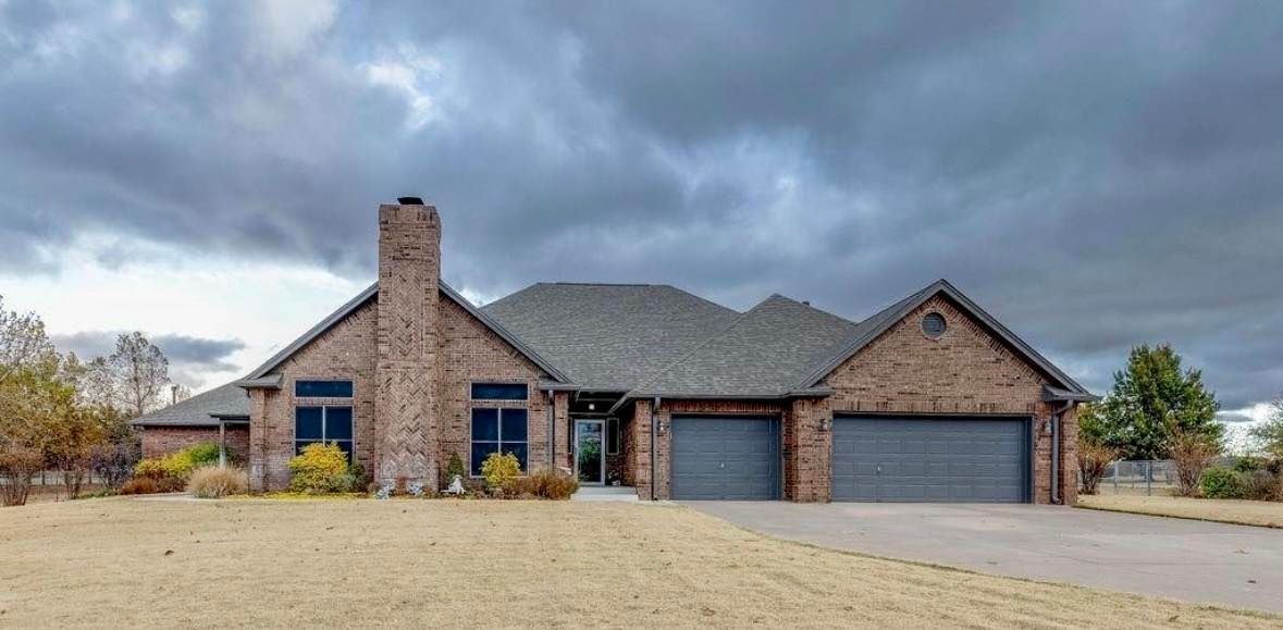 Brick house with a gray roof and two-car garage under a cloudy sky.
