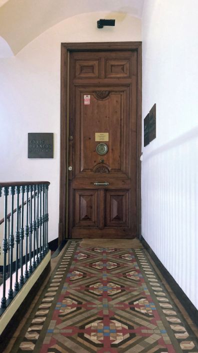 Un pasillo con una puerta de madera y una alfombra en el suelo.