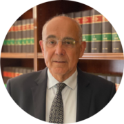 Un hombre con traje y corbata está de pie frente a una estantería.