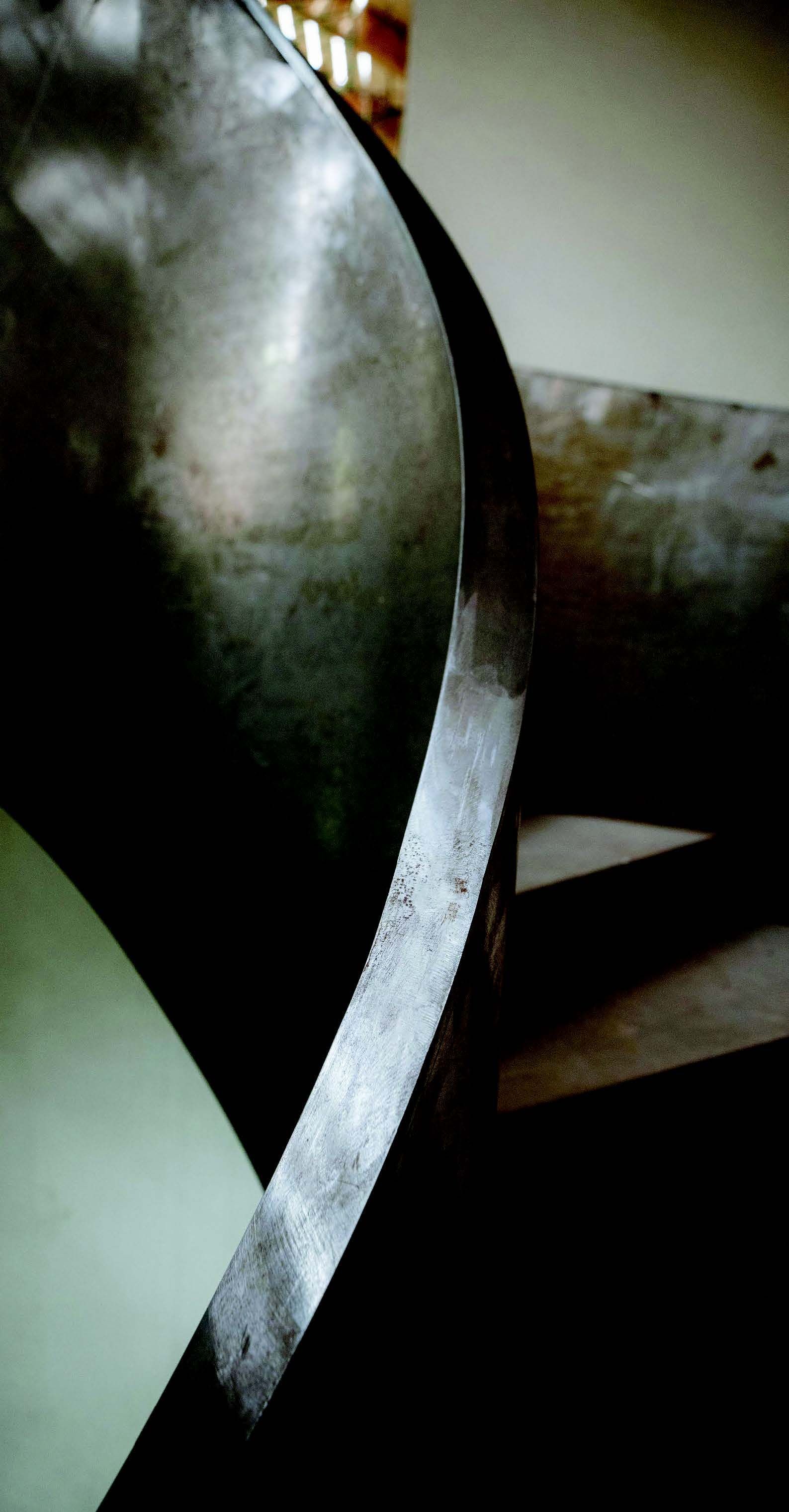 Blaue Bushaltestelle mit Bank und Schild auf einem Gehweg neben einer Straße.