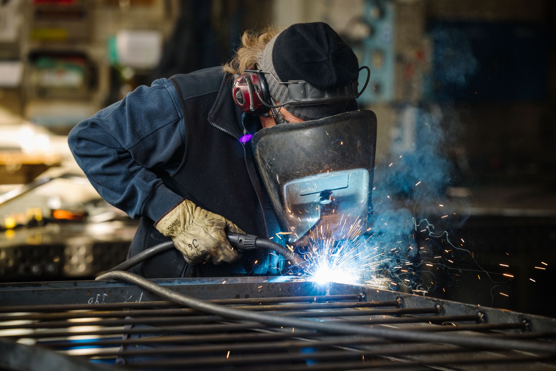Schweisser mit Schutzmaske arbeitet an Metall, Funken sprühen.
