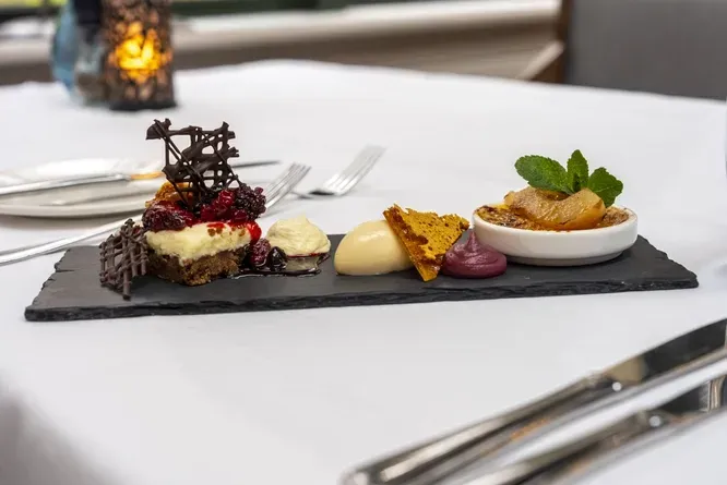 A plate of desserts on a slate tray on a table.