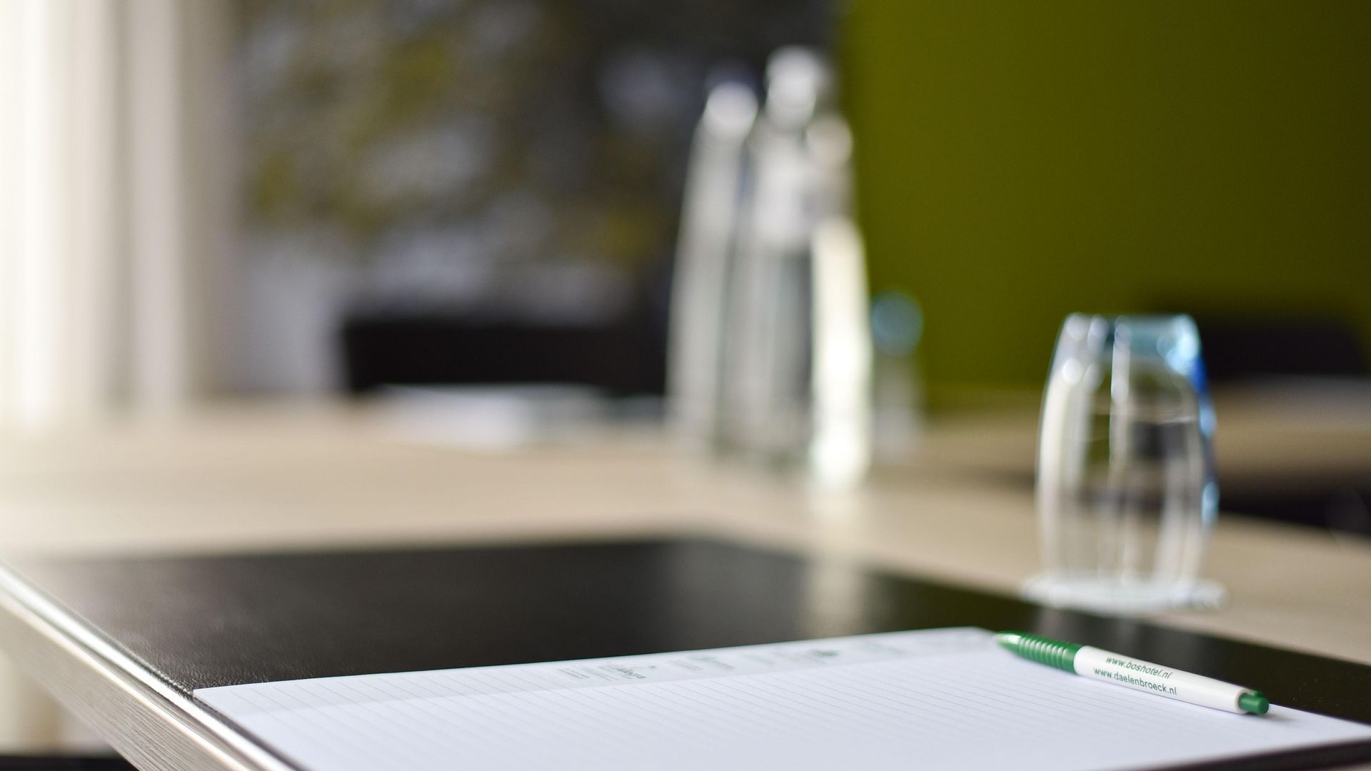 A table with a notebook , pen , and glasses on it.