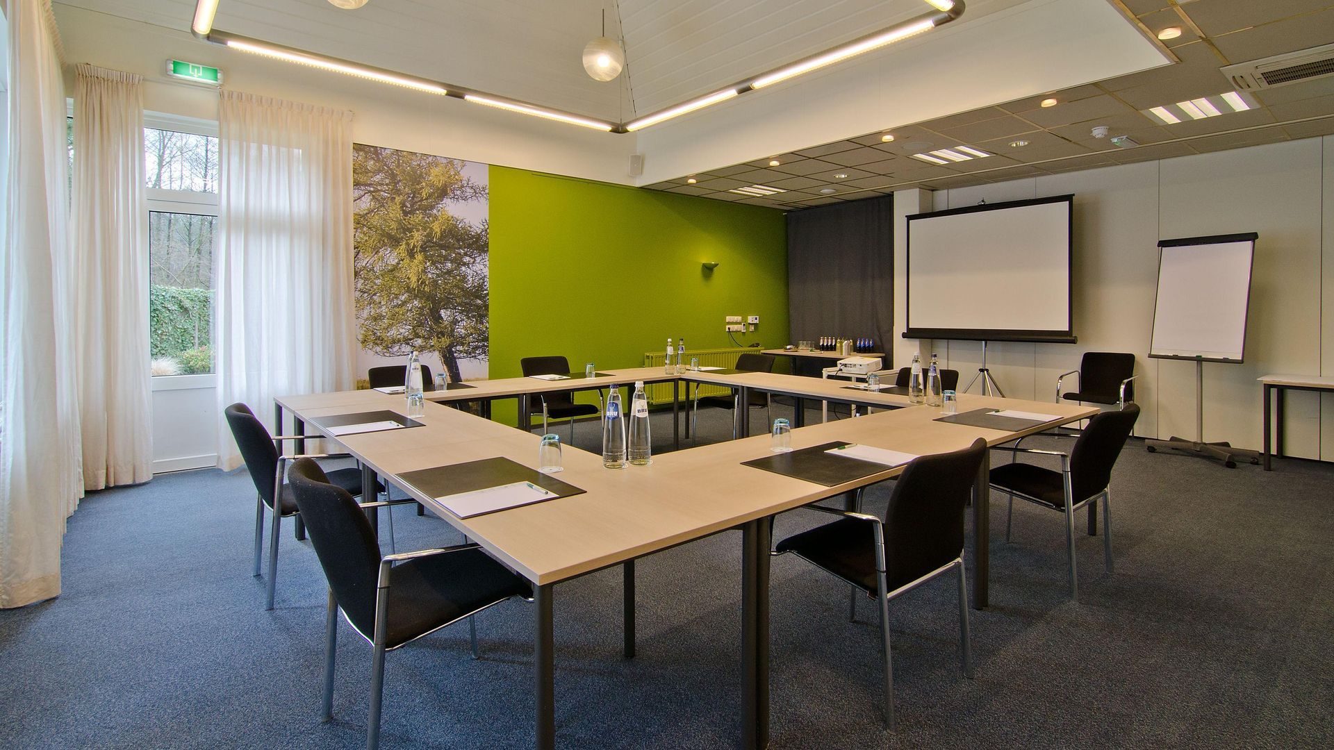 Ein Konferenzraum mit Tischen und Stühlen sowie einer Projektionsleinwand.