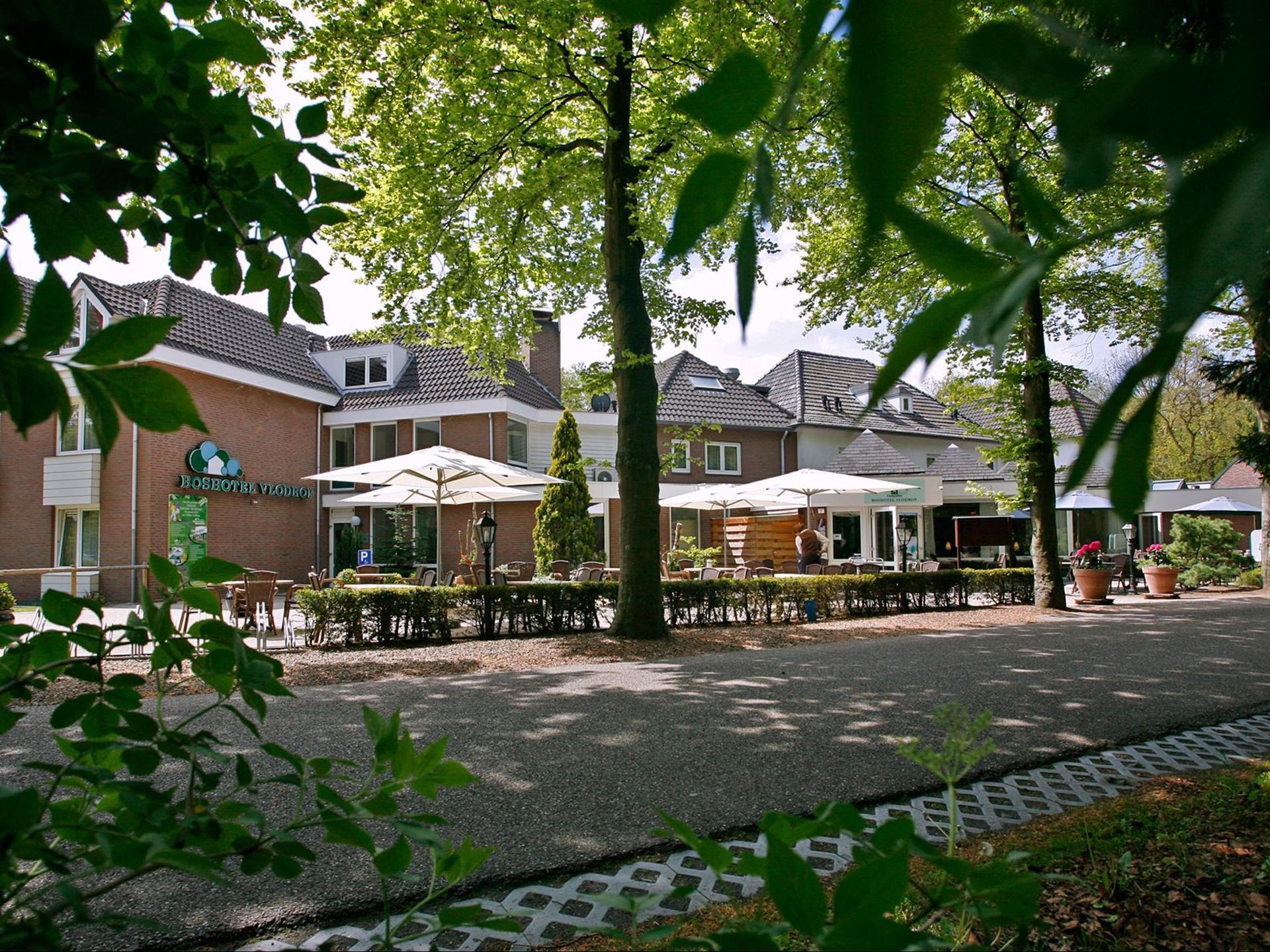 Ein Backsteingebäude mit Tischen und Sonnenschirmen davor