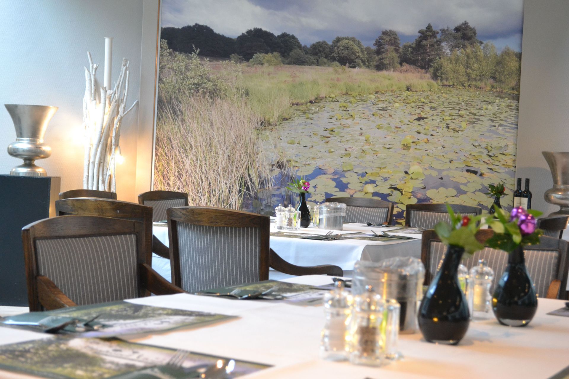 A dining room with tables and chairs and a large picture on the wall