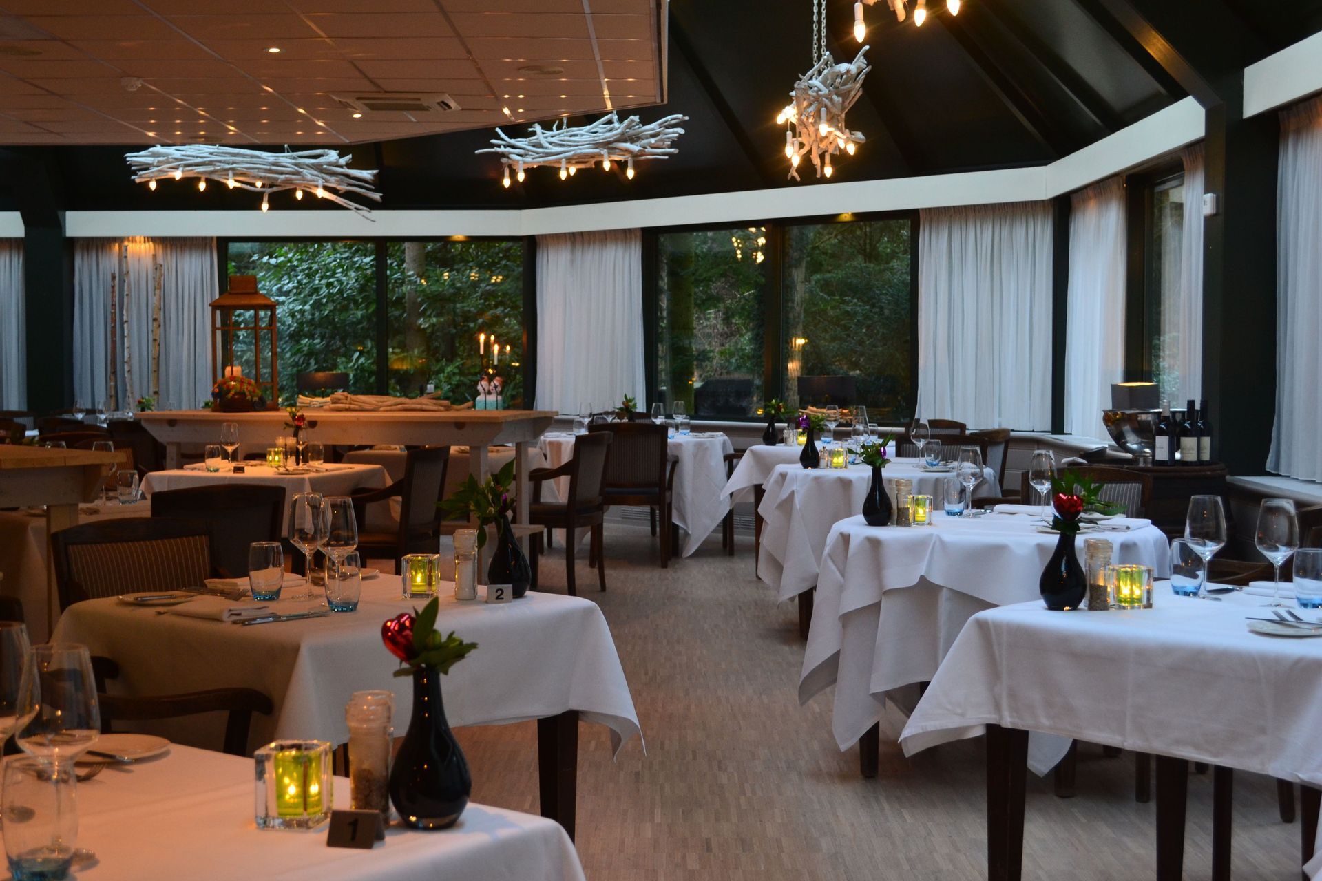 Een restaurant met tafels, stoelen en kaarsen erop