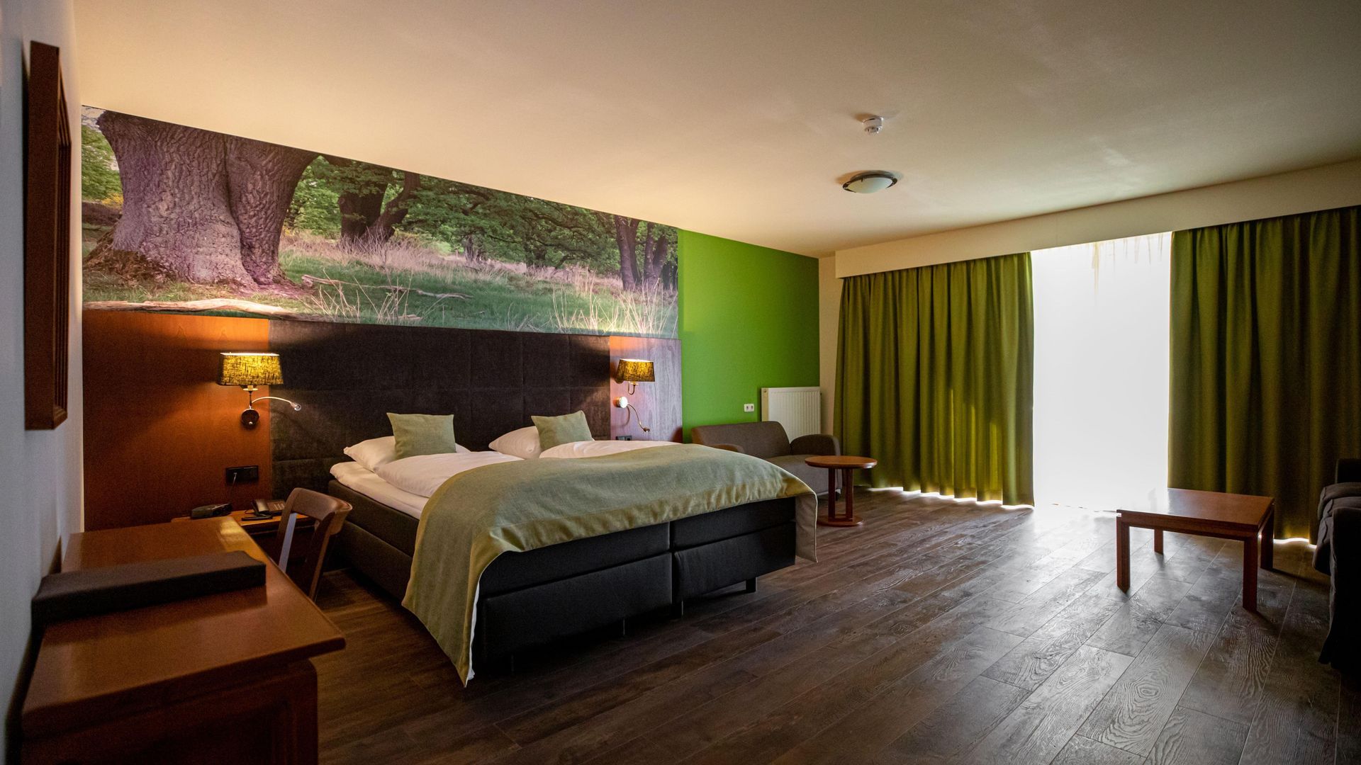 Een hotelkamer met een groot bed en groene gordijnen.