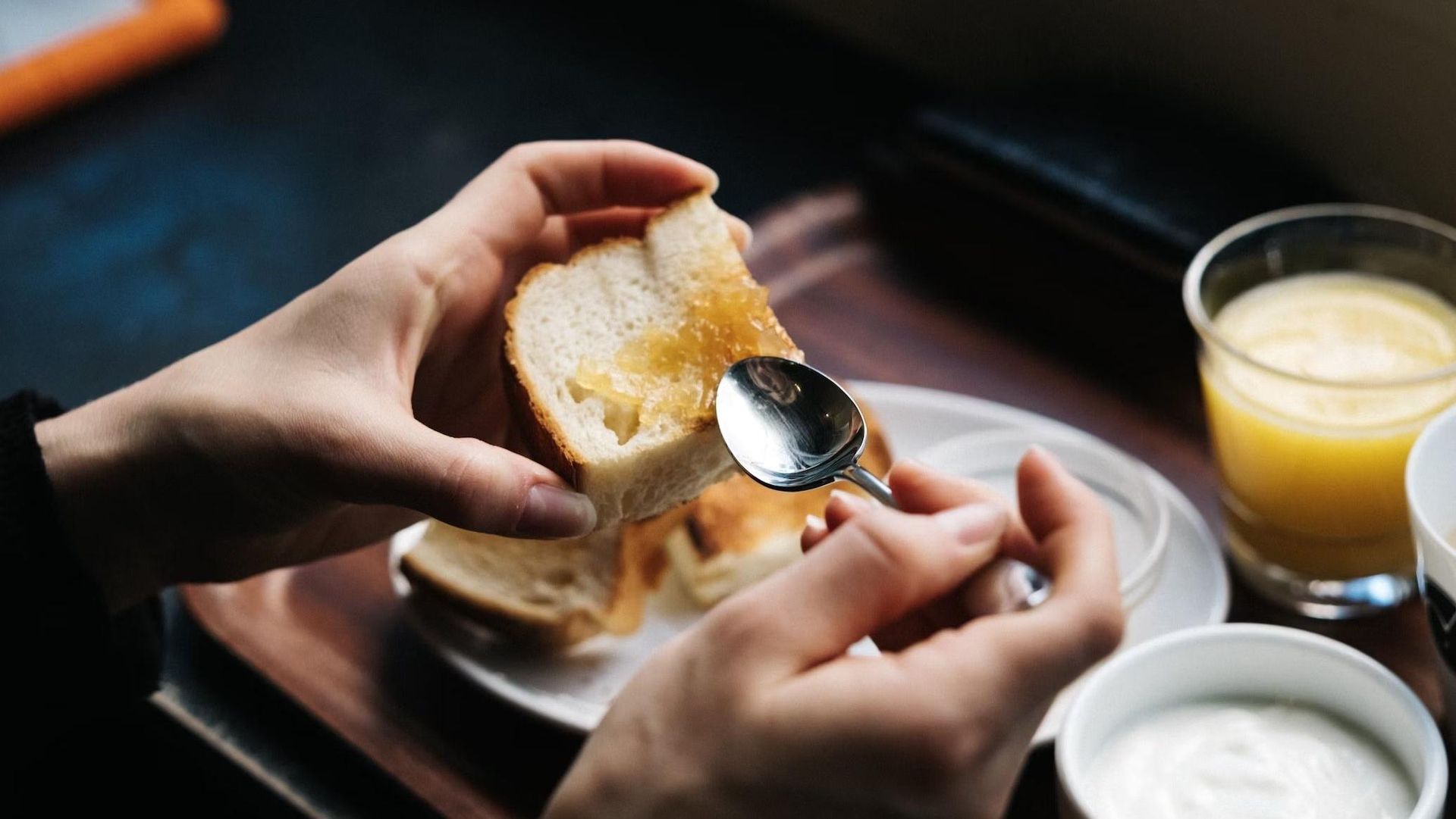 A person is spreading butter on a piece of bread with a spoon.