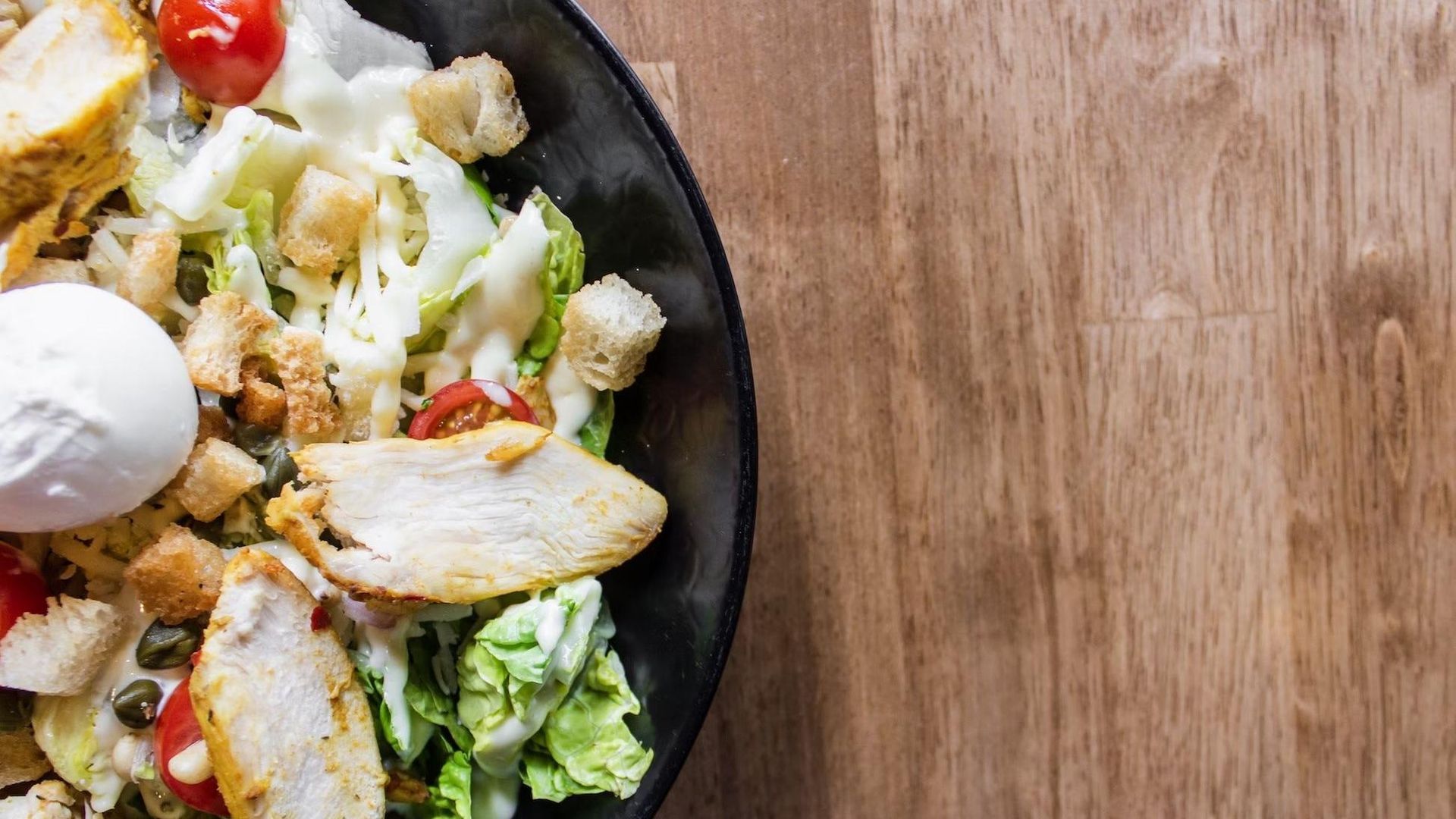 A close up of a salad on a plate on a wooden table.