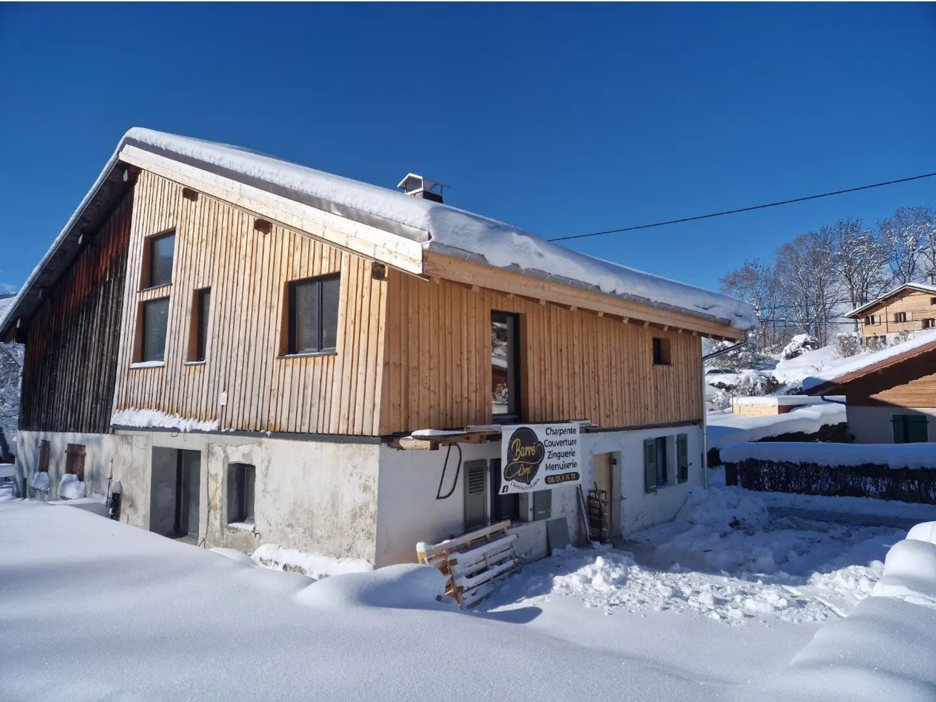 Maison après rénovation avec bardage en bois sur l'étage, la maison enneigée.
