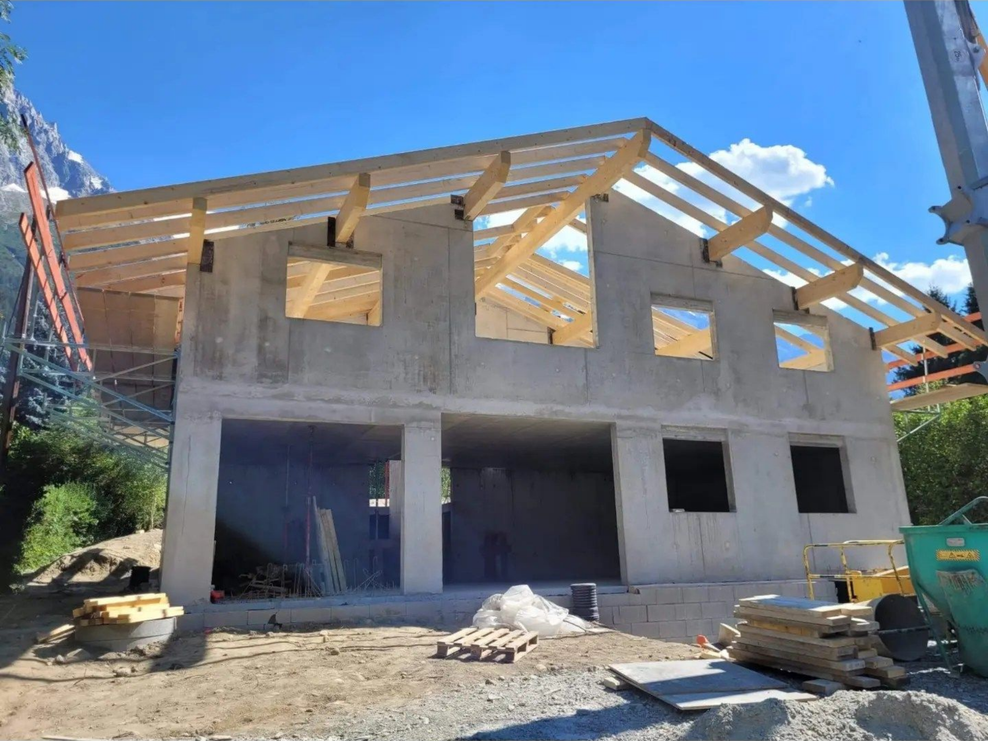 Chantier : bâtiment en béton avec charpente en bois.