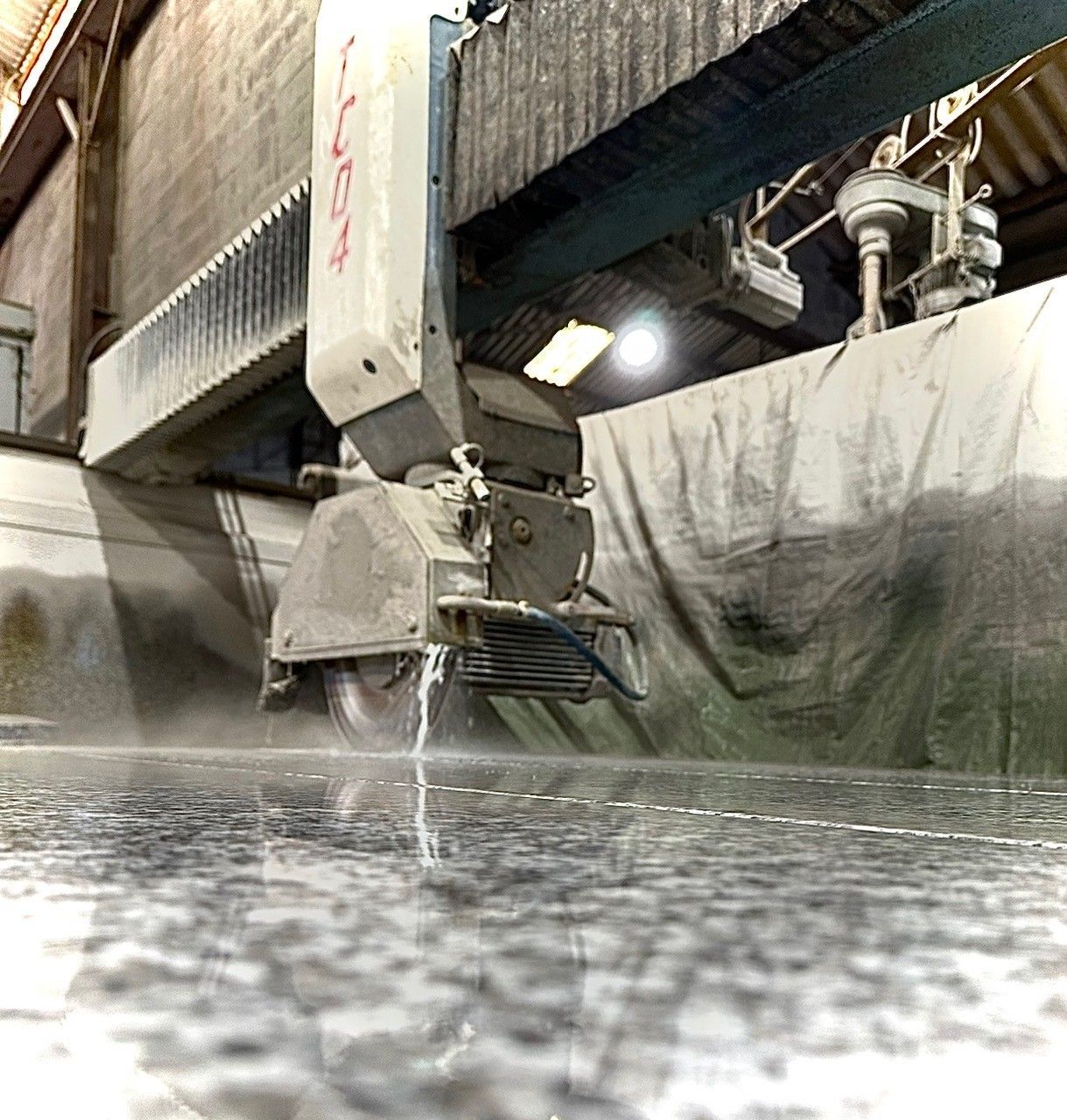 Machine de découpe de pierre sciant du granit humide dans un environnement industriel.