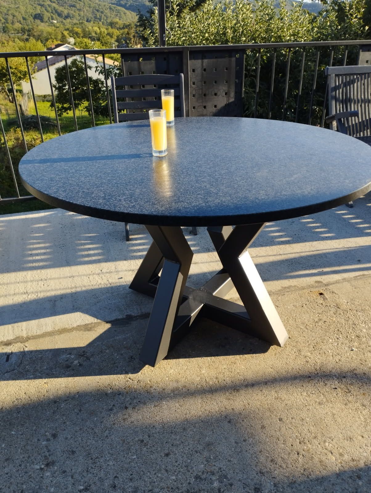 Table ronde noire avec jus d'orange, décor de patio extérieur.