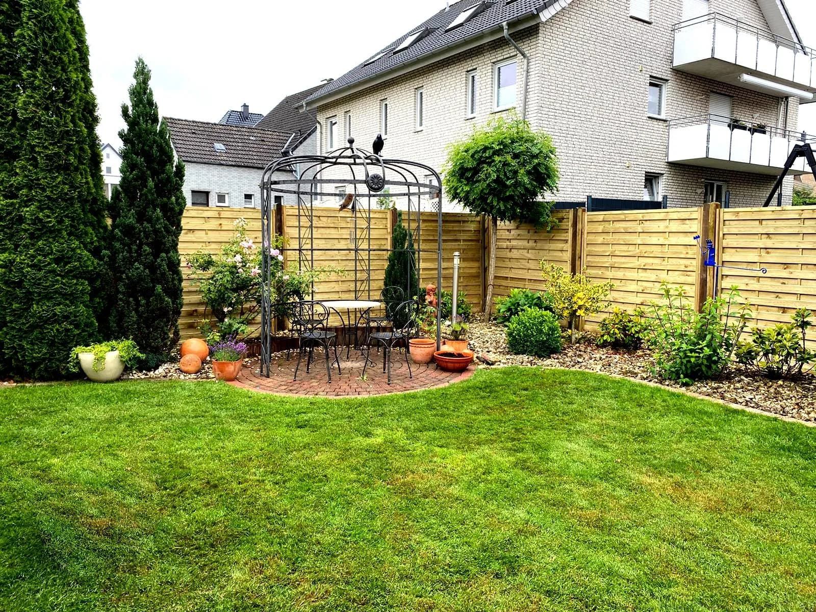Ein Garten mit Pavillon und Tisch und Stühlen vor einem Haus.