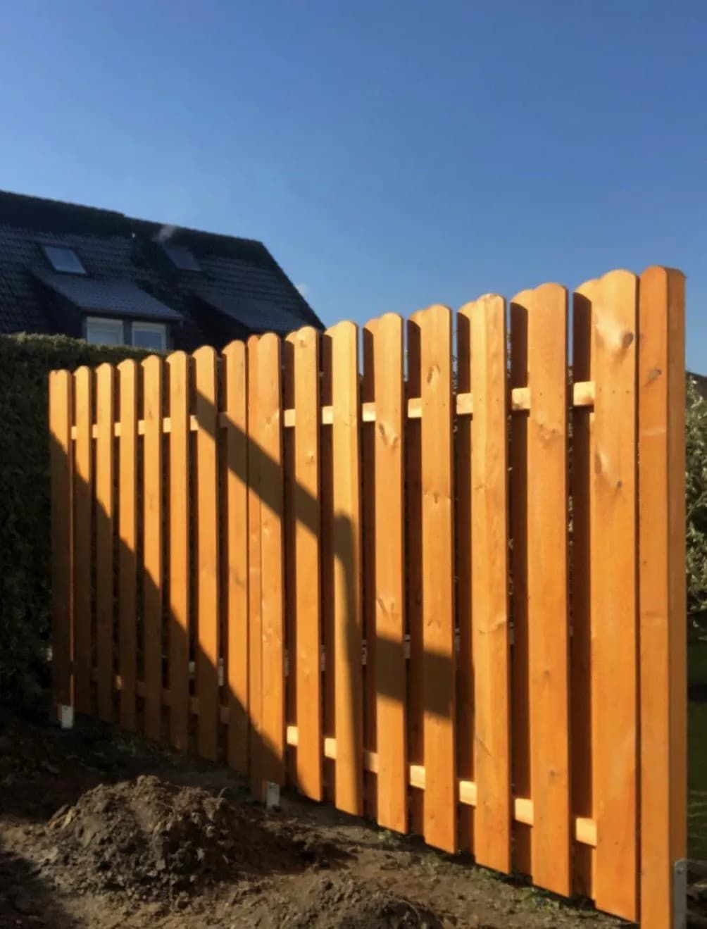 Ein Holzzaun mit einem Haus im Hintergrund