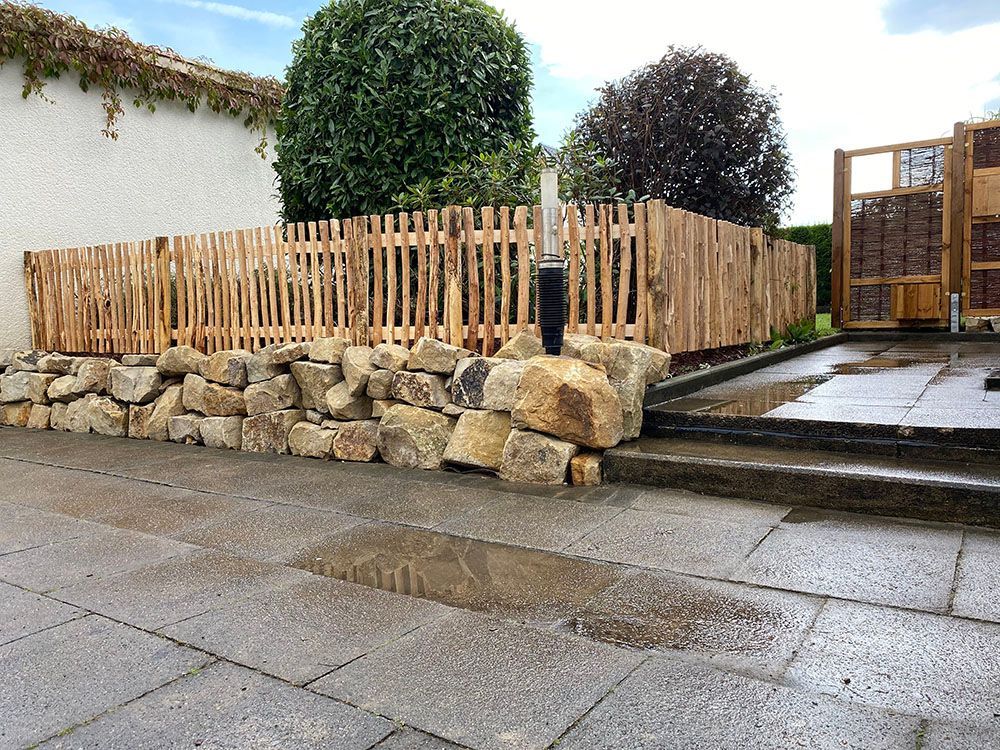 Ein Holzzaun ist von Felsen und einer Steinmauer umgeben.