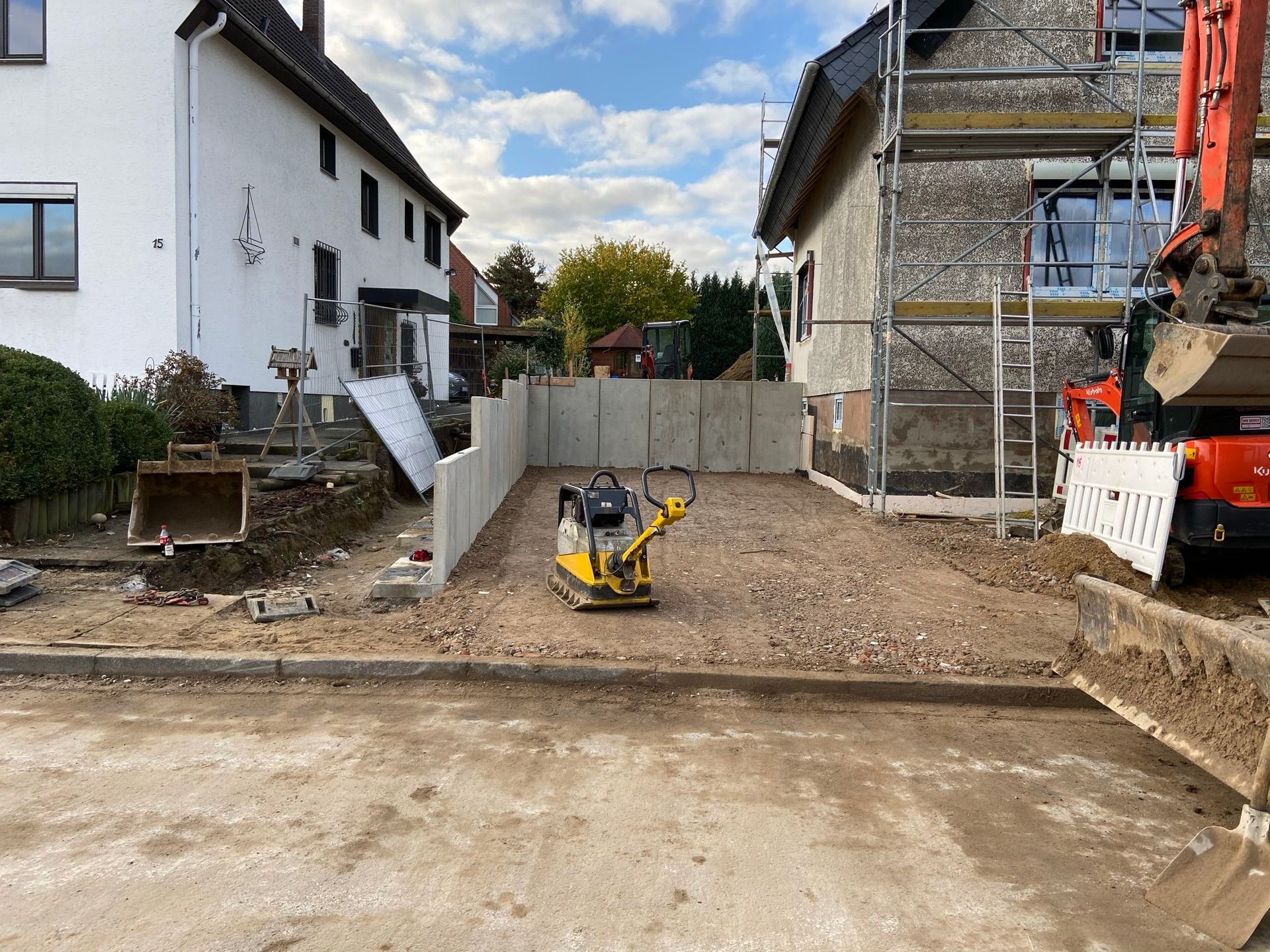Eine Baustelle mit einem Haus im Hintergrund und einem Traktor im Vordergrund.