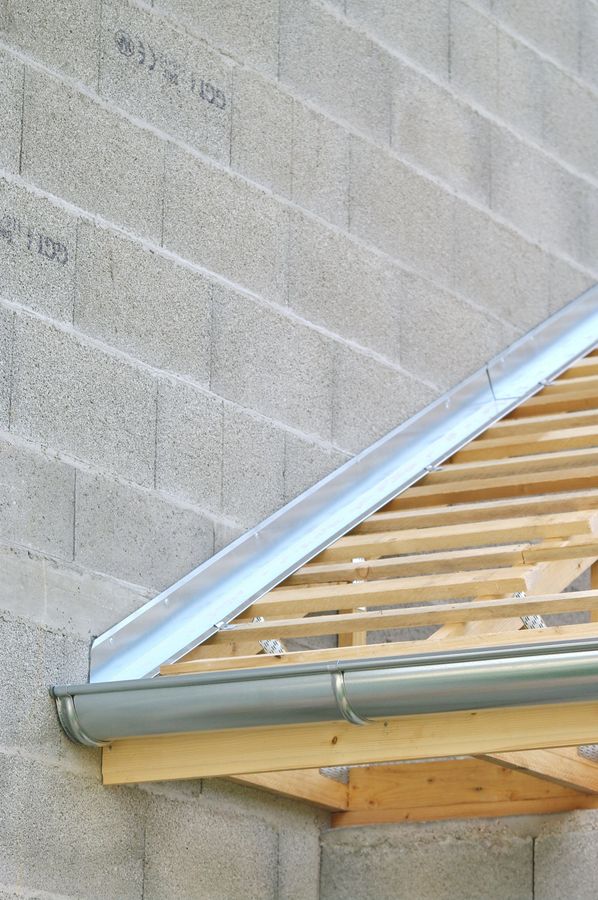Jonction du toit au mur en zinc pour faciliter l'écoulement de l'eau ainsi que la gouttière sur un toit en rénovation
