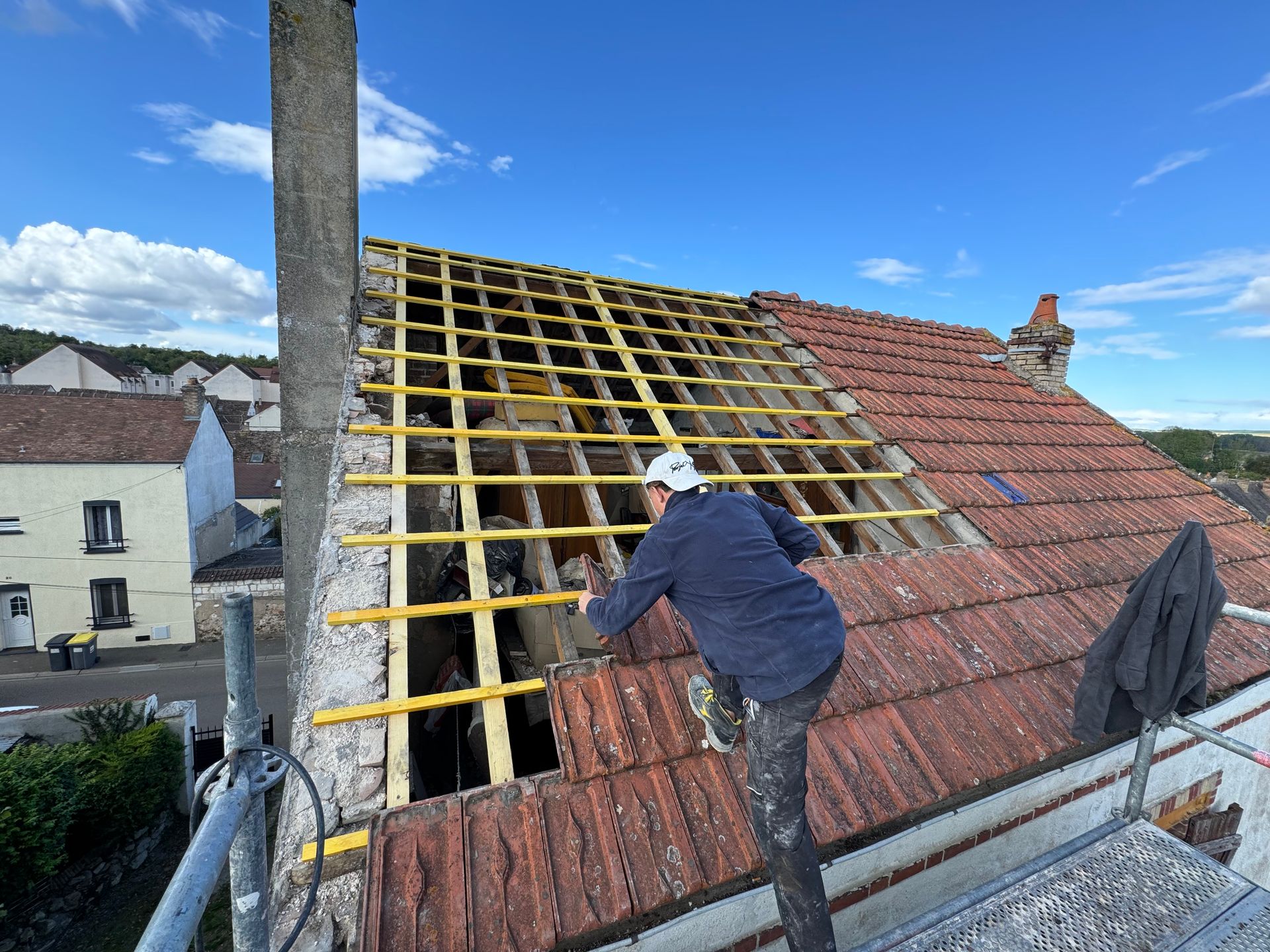 Avant la rénovation de la toiture, un ouvrier repose les tuiles sur la nouvelle toiture
