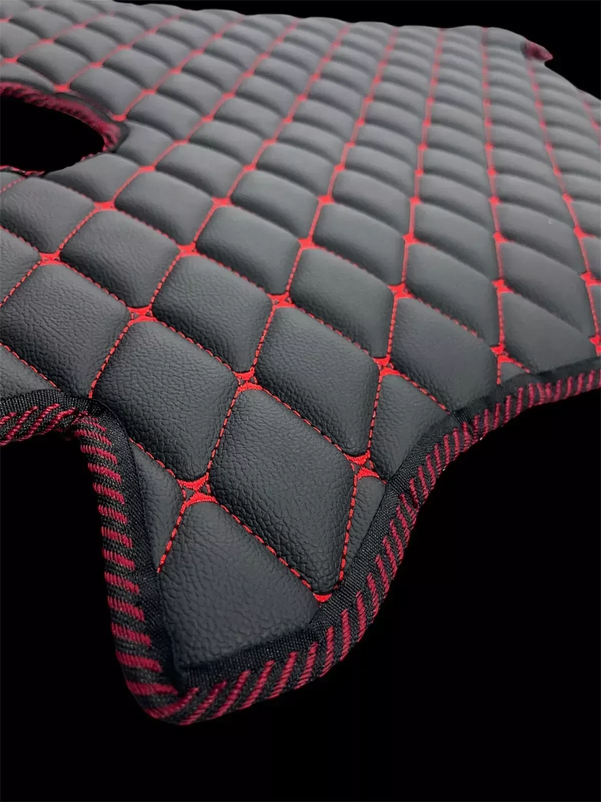 Eine Nahaufnahme einer schwarz-roten Steppmatte auf schwarzem Hintergrund.