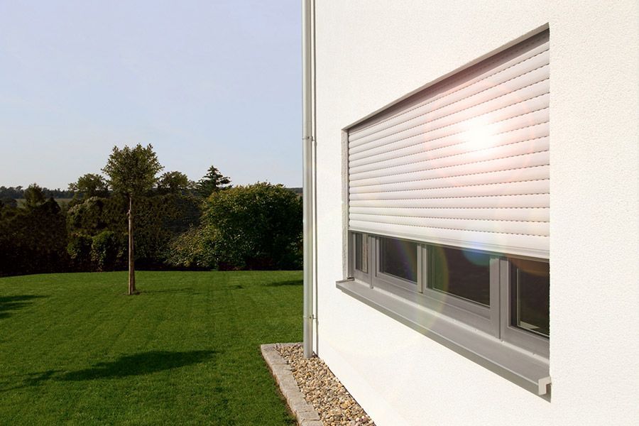 Ein weißes Haus mit einem Fenster mit Rollladen.