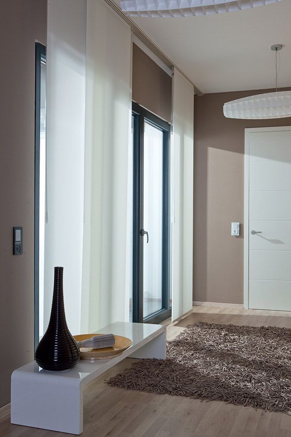 Eine Vase steht auf einer Bank in einem Flur neben einem Fenster.