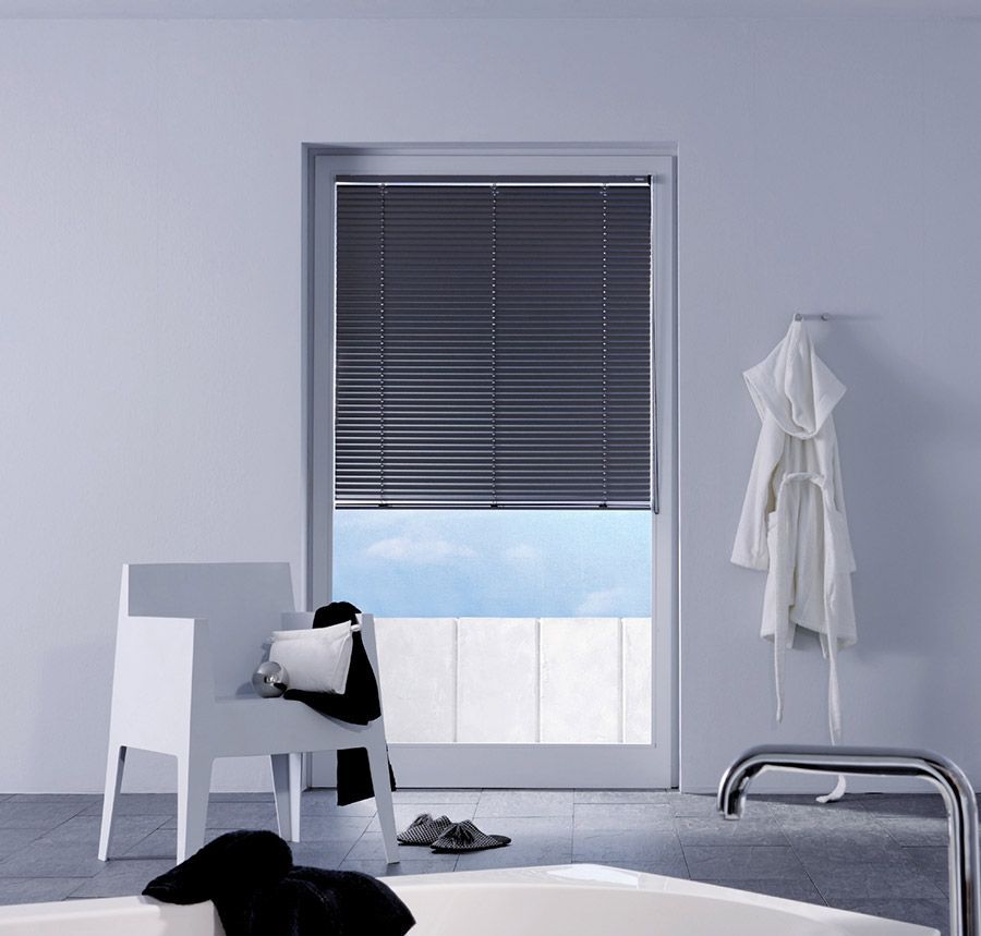 Ein Badezimmer mit Badewanne, Stuhl und Fenster mit Jalousien