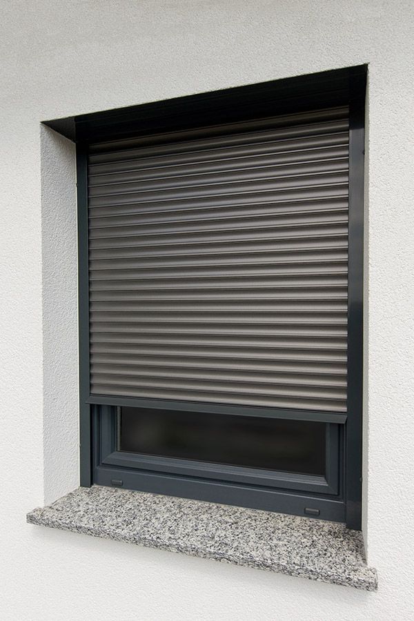 Ein Fenster mit einem grauen Rollladen daran