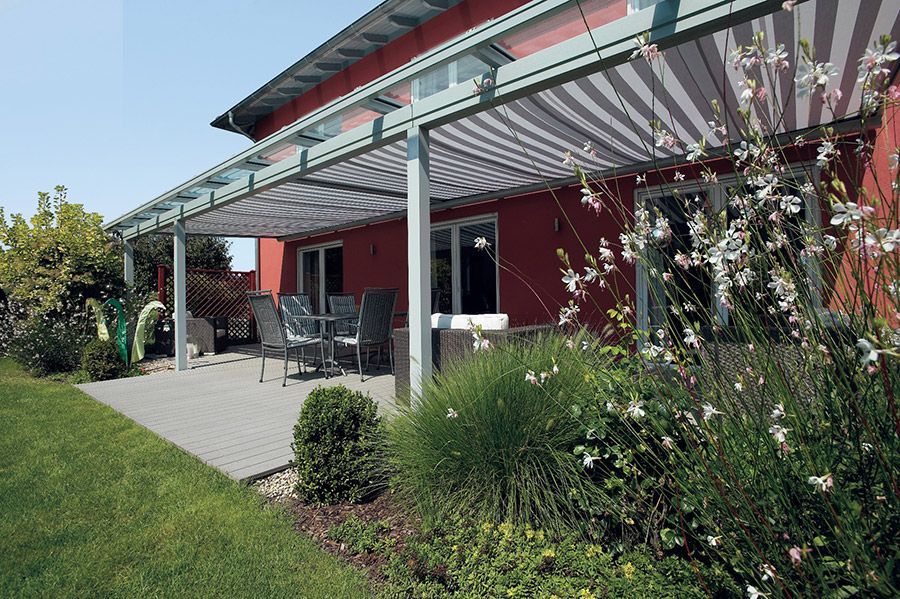 Ein rotes Haus mit einer Terrasse mit gestreifter Markise
