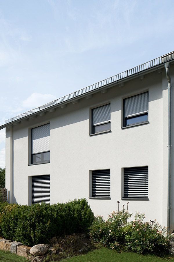 Ein weißes Haus mit schwarzen Jalousien an den Fenstern