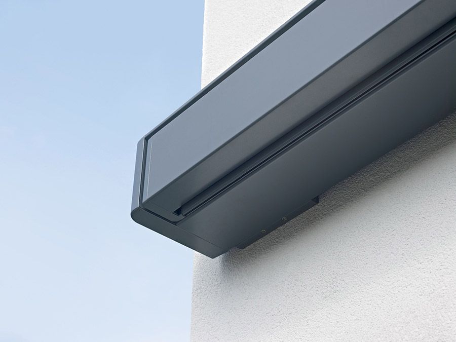 An der Seite eines Gebäudes ist eine schwarze Markise angebracht.