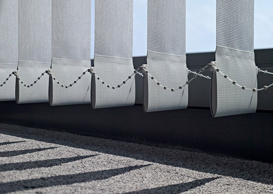 An einem Fenster hängt eine Reihe vertikaler Jalousien.