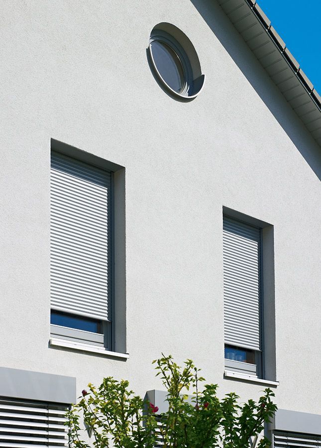 Ein weißes Haus mit einem runden Fenster auf dem Dach
