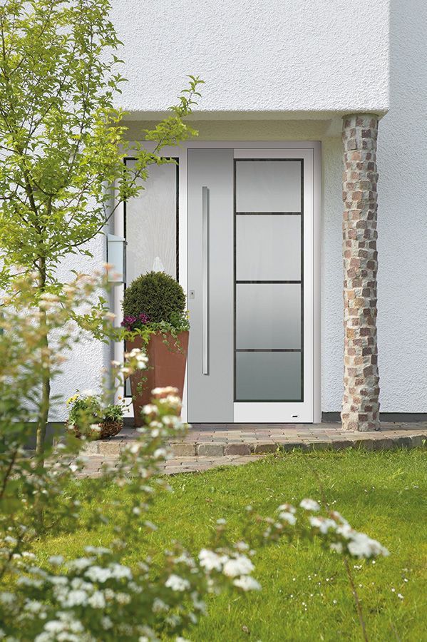 Vor einem weißen Haus steht eine weiße Tür mit einem Edelstahlgriff.