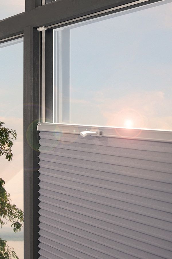 Ein Fenster mit einer Jalousie, durch das die Sonne scheint.