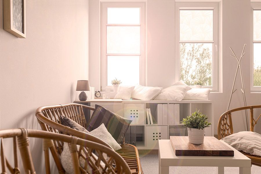 Ein Wohnzimmer mit einer Couch, Stühlen, einem Tisch und einem Fenster.