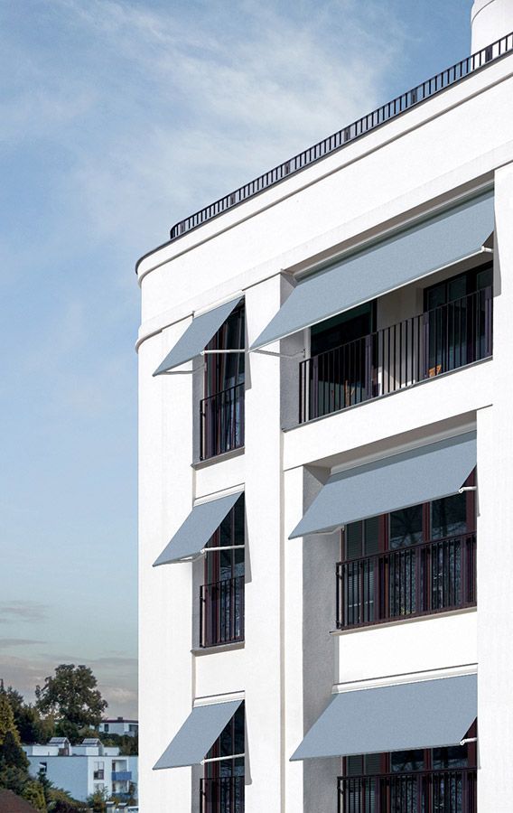 Ein weißes Gebäude mit Balkonen und Markisen an den Fenstern