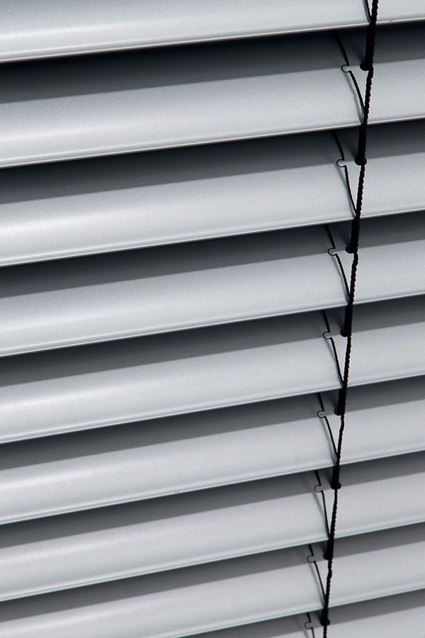 Eine Nahaufnahme einer Reihe weißer Jalousien an einem Fenster