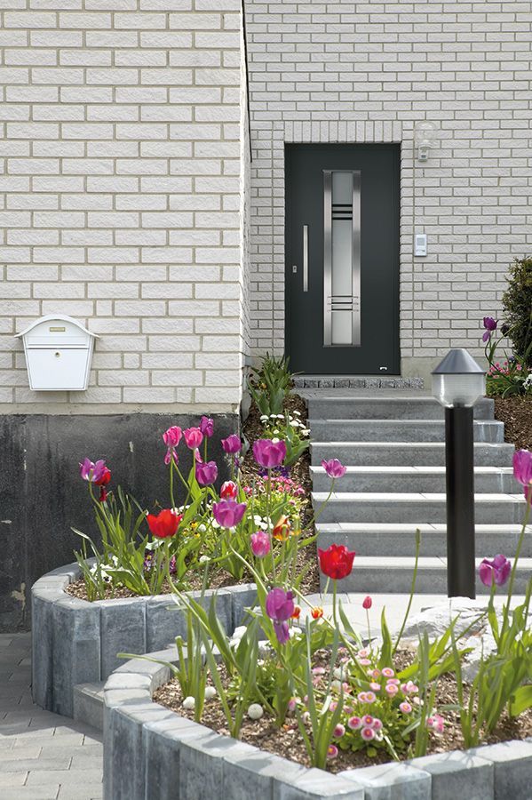 Ein weißes Backsteingebäude mit einer schwarzen Tür und einer Treppe, die dorthin führt