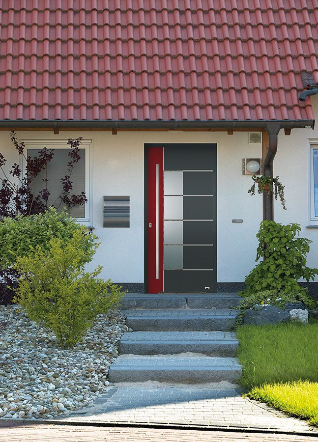 Ein weißes Haus mit einem roten Dach und einer schwarzen Tür
