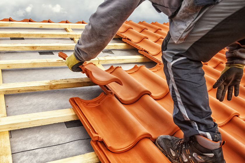 Professionnel posant des tuiles sur une toiture