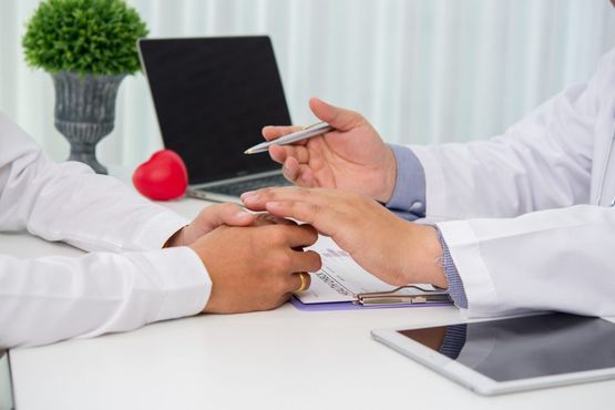 Arzt macht erklärende Geste im Gespräch mit einem Patient