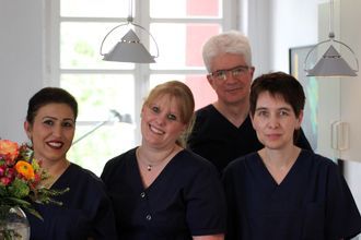 Person mit Gebissmodell und zahnärztlichem Instrument in der Hand